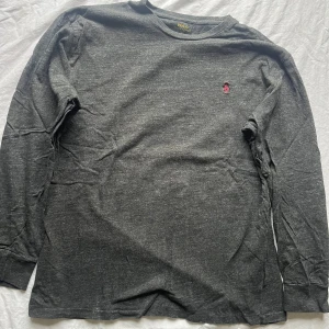 Grå långärmad tröja från Polo Ralph Lauren - Säljer en stilren grå långärmad tröja från Polo Ralph Lauren i storlek M. Tröjan har en liten broderad logga i rött på bröstet. Perfekt för både vardag och lite finare tillfällen. Skön och enkel att matcha med det mesta. Hör av dig vid intresse!