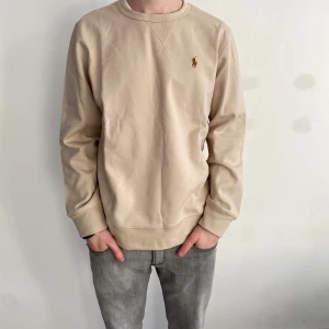 Ralph lauren tröja - Säljer en Ralph Lauren tröja i färgen beige. Den är i storleken M och sitter lite stort på mig som är 180, 67kg. Hör av dig vid frågor och funderingar.