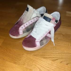 Säljer ett par unika sneakers i mycket bra skick. De har en cool kombination av röd och rosa färg med ett häftigt mönster på sidorna. Skorna har snörning och en bekväm passform. Perfekta för att sticka ut i mängden!