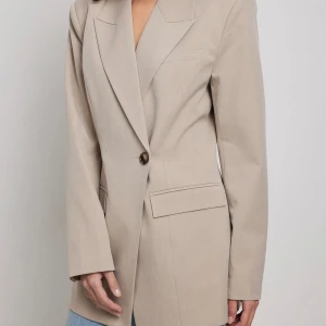 Beige kavaj med knappar - Snygg beige kavaj i normal passform med en enkel knapp framtill. Perfekt för både vardag och fest. Den har långa ärmar och stilrena fickdetaljer. Passar bra till jeans eller kjol för en chic look.  Lite stor i storleken. Passar perfekt till XS-S✨