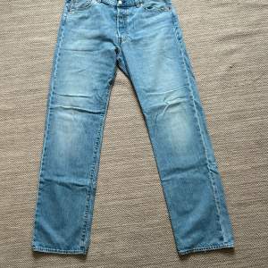 Säljer ett par klassiska Levi's 501 jeans i ljusblå denim. W36/L34, de har en straight passform och är i bra skick. Perfekta för både vardag och avslappnade tillfällen. Jeansens ikoniska design gör dem tidlösa och lätta att matcha med olika stilar.