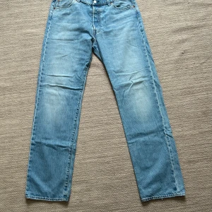 Levi's 501 ljusblå jeans - Säljer ett par klassiska Levi's 501 jeans i ljusblå denim. W36/L34, de har en straight passform och är i bra skick. Perfekta för både vardag och avslappnade tillfällen. Jeansens ikoniska design gör dem tidlösa och lätta att matcha med olika stilar.