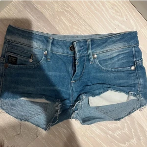 Blå jeansshorts från G-Star - Säljer ett par snygga blå Lågmidjade jeansshorts från G-Star i bra skick. De är lågmidjade med slitna detaljer❤️