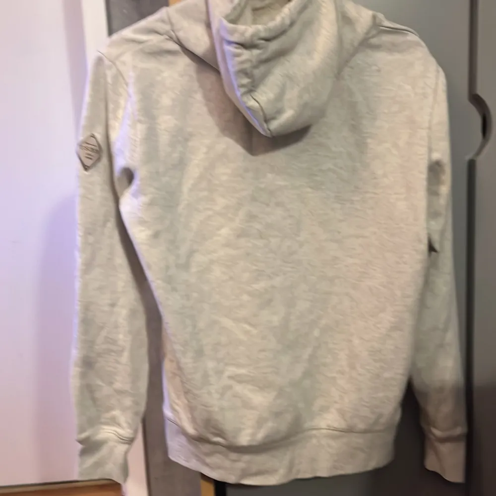 Säljer en snygg beige hoodie i storlek S. Den har en skön känguruficka och justerbar huva med dragsko. Perfekt för en avslappnad stil och passar bra till både höst och vår. Slim fit för en modern look!. Tröjor & Koftor.