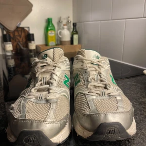 New Balance 530 sneakers - Säljer ett par New Balance 530 sneakers i vitt och grönt. Perfekta för både vardag och träning. De har en bekväm passform och är gjorda i syntetmaterial med meshdetaljer för extra andningsförmåga! Skorna har lite slitningar i meshtyget fram vid småtårna (se bilder), men är lagade med laglappar. Skickar med nya vita skosnören 🫶🏻 fint skick utöver anmärkningarna! 