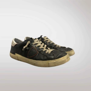 Svara philippe models - Säljer ett par svarta sneakers i bra skick med vita snören och detaljer. De har en cool, sliten look med en vit sula som ger en vintage känsla. Perfekta för vardagsbruk och passar till nästan allt. Sköna och stilrena!