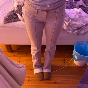 Beige byxor med knappar - Säljer ett par snygga beige byxor i nytt skick, endast använda en handfull av gånger. Bootcut och lowwaist. Unika med knappar framtill. Perfekta för både vardag och fest! Klippt bort lappen med storleken på, men passar mig perfekt som har Xs/s på byxor💕