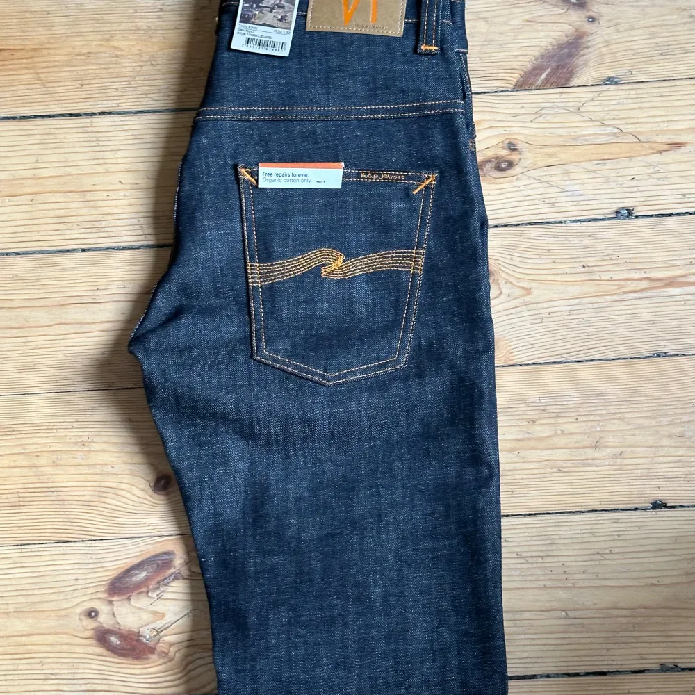 Ett par helt oanvända Nudie Jeans! Modell är Thinn Finn, alltsà slim fit. W30 L32 Helt oanvända, endast prövade. Alla lappar sitter kvar. Inga defekter eller nägot alls. Säljer pga inte passar mig De är mörkt mörkblà med orangea detaljer. PRIS ÄR DISKUTERBART. Jeans & Byxor.