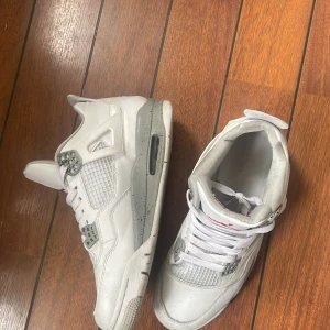 Vita Nike Air Jordans - Säljer ett par vita Nike Air Jordans i storlek 42.5. Skorna har en snygg design med grå detaljer och är i bra skick. Perfekta för både vardag och fest!