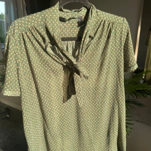 Grön tröja - Fin grön mönstrad tröja. Skönt och tunnt material med gullig rosett fram som man kan knyta hur man vill.