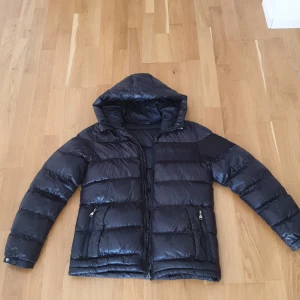 Svart pufferjacka från Alessandro Zanetti - Säljer en snygg svart pufferjacka från Alessandro Zanetti. Jackan har en glansig finish och är perfekt för kalla dagar.  Jackan är i bra skick och redo för vintern!               Ny pris: 1 300