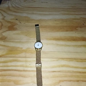 Guldfärgad klocka från Zone - Säljer en stilren guldfärgad klocka från Zone. Den har en vit urtavla med minimalistisk design och ett mesh-armband i guld. Perfekt för både vardag och fest! 🕒✨