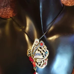 Brosch/Hänge - Fjäril med kedja - Den här broschen i form av en fjäril i multifärger (kristaller) är ca 6.5 × 3.5 cm. Medföljer en halskedja, se bilder.