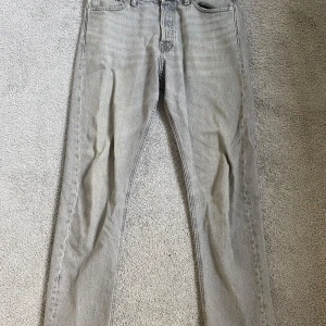 Grå jeans från Jack & Jones - Säljer ett par snygga grå jeans från Jack & Jones i modellen Loose/Chris. De har en loose passform och är perfekta för en avslappnad stil. Jeansen har en klassisk femficksdesign och är i bra skick. Perfekta för både vardag och fest!