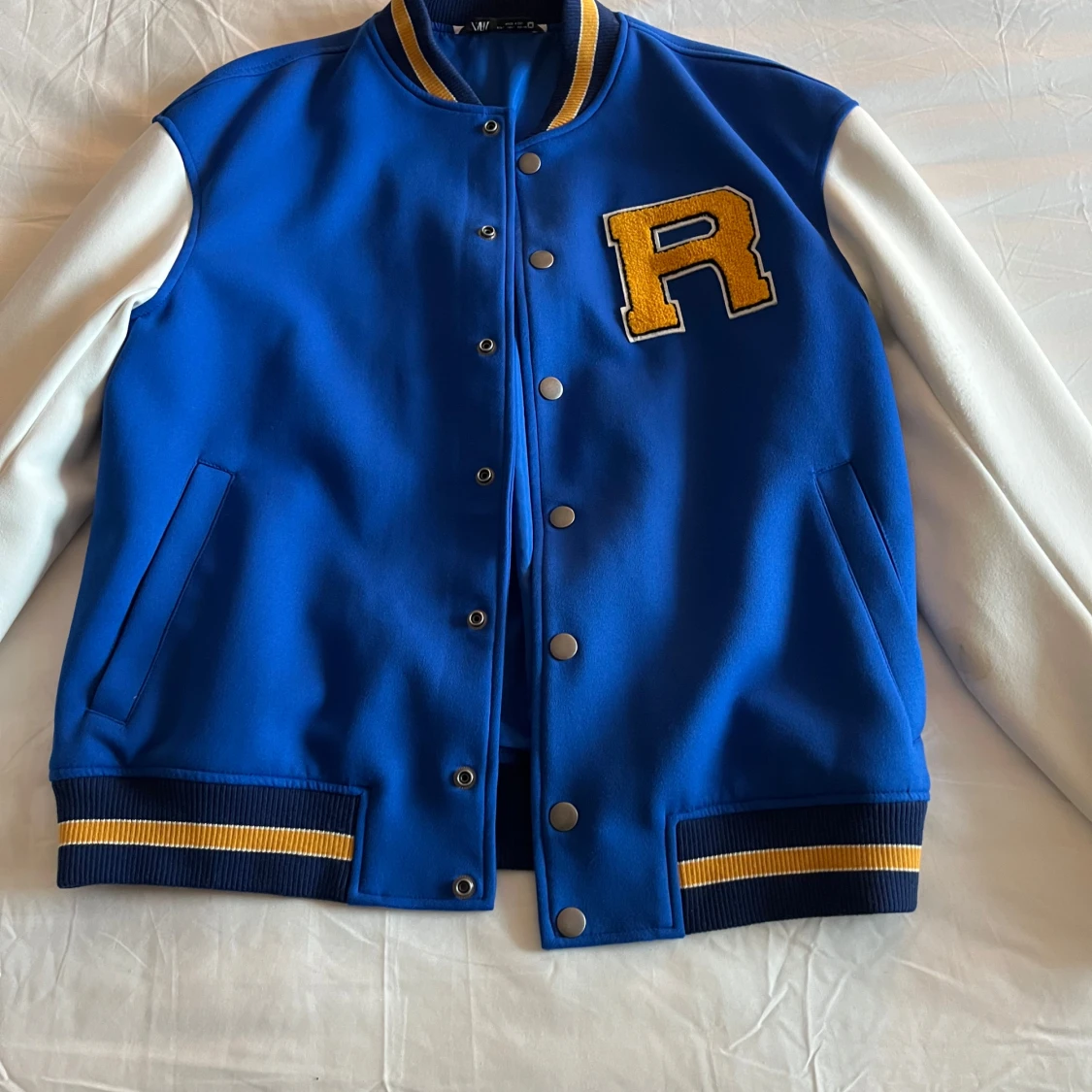 Blå och vit bomberjacka med bokstavsdetalj