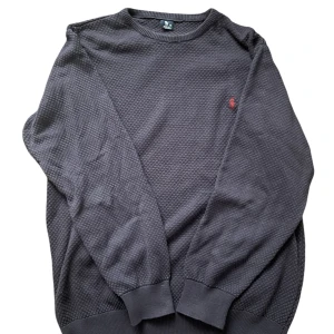 Mörkgrå tröja från Polo Ralph Lauren - 💎| Säljer en stilren mörkgrå tröja från Polo Ralph Lauren med ett diskret mönster och röd logga på bröstet. Tröjan har långa ärmar och ribbade muddar vid ärmslut och nederkant. Perfekt för en avslappnad men snygg look.                                                📬| Skickas inom 24 timmar!