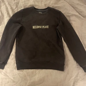 Svart sweatshirt från A.P.C. - Säljer en stilren svart sweatshirt från A.P.C. med texten 'Melrose Place' tryckt på framsidan. Hyfsat välanvänd, men inte något märkvärdigt 