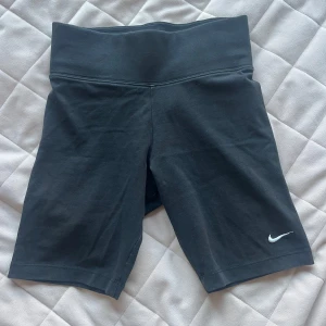 Svarta cykelshorts från Nike - Säljer ett par svarta cykelshorts från Nike med en liten vit logga på benet. De har en hög midja och i bomull. 