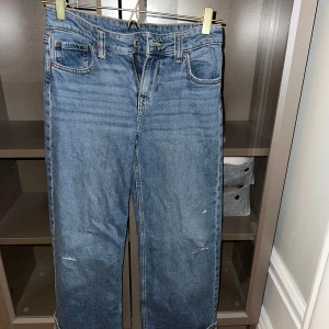 Blå jeansbyxor - Snygga blå jeansbyxor med en klassisk femficksdesign och dragkedja. De har en rak passform och är perfekta för en avslappnad stil. Byxorna har en lätt slitning på framsidan för en trendig look.