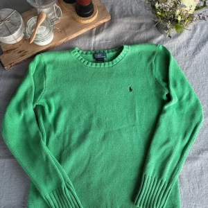 Grön stickad tröja från Polo Ralph Lauren - Säljer en snygg grön stickad tröja från Polo Ralph Lauren. Tröjan har en klassisk rund halsringning och ett diskret broderat märke på bröstet. Perfekt för en stilren look. 💚