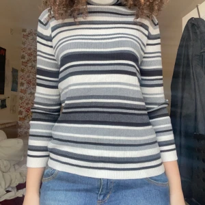 Randig polotröja i svart och vit - Säljer en snygg randig polotröja i olika nyanser av svart och vitt. Tröjan har långa ärmar och en bekväm passform, perfekt för kyligare dagar. Passar bra till jeans eller kjol!