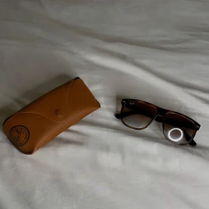 Bruna solglasögon från Ray-Ban - Snygga bruna solglasögon från Ray-Ban med en klassisk fyrkantig form. De är en snygg modell som är väldigt trendig, det medföljer ett brunt skyddsfodral. Perfekta för en stilren look. Missa inte att köpa dem de kommer vara stilrena inför sommaren.