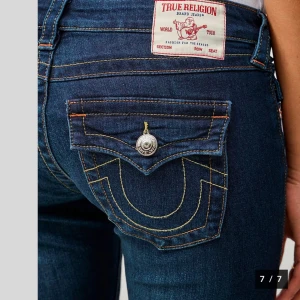 Mörkblå bootcut jeans från True Religion - Snygga mörkblå bootcut jeans från True Religion med ikoniska bakfickor och kontrastsömmar. Perfekta för en stilren look med en touch av retro. Märkeslappen syns tydligt på baksidan. Inte mina bilder kom privat för egna❤️❤️❤️