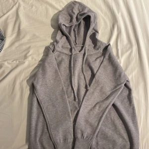 Merinoulls hoodie - Säljer en stilren grå hoodie med långa ärmar och justerbar huva. Perfekt för en avslappnad look. Den har ribbade muddar vid ärmslut och nederkant för extra komfort.