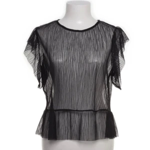 Svart transparent blus från MNG Casual - Säljer en superfin svart transparent blus från Mango Casual. Den har korta ärmar med volangdetaljer och en luftig passform. Perfekt för en kväll ute eller en festlig tillställning. Passar bra över ett linne eller en snygg bh.