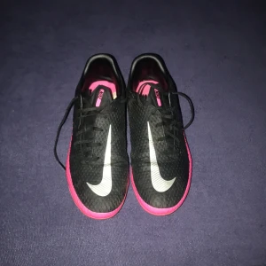 Svarta och rosa Nike fotbollsskor - Säljer ett par svart,rosa fina skor med en cool design. Storleken på skorna är 38 det är utomhusskor och är väldigt sköna och bra vi kan diskutera men vi börjar med 400kr.