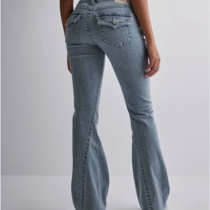 True Religion jeans i ljusblå denim - Säljer mina nästintill helt nya par True Religion jeans i ljusblå denim. Använda högst 5 ggr! De är lågmidjade och bootcut. Jeansen har de klassiska True Religion detaljerna med snygga sömmar och knappar. Nypris 1299kr