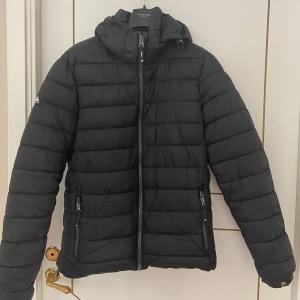 Superdry jacka - Säljer denna Superdry jackan. Perfekt till vintern. Riktigt varm och skön. Storlek S. Passar perfekt om du är ungefär 175-181 cm lång. Den har ett litet hål i luvan men det syns inte om man inte kollar jättenära. 