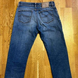  Jacob Cohën Jeans - Säljer ett par jeans från Jacob Cohën. Storlek 32.  Slitningar på båda benen för en trendig look.  Handgjorda i Italien, perfekta för dig som letar efter hög kvalitet och trendiga jeans.