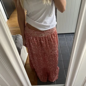 Röd paisleymönstrad långkjol - Hela kjolen är 97cm lång. Säljer en snygg röd/rosa långkjol med paisleymönster. Kjolen har en bekväm passform och är perfekt för varma dagar. Den är gjord i ett lätt och luftigt material som ger en skön känsla. Nypris 500kr. Storlek M men passar mer S, lite liten i storleken 