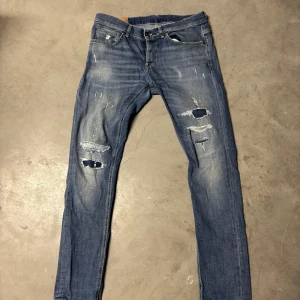 Dondup jeans - Snygga blå jeans från Dondup med slitna detaljer och en skinny passform. De har en klassisk femficksdesign och en knappgylf. Perfekta för en avslappnad stil. På bilderna finns bilder på defekterna. 