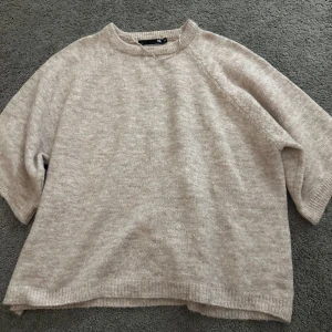 Beige stickad tröja från 157 - Mysig beige stickad tröja från 157 i storlek XS. Tröjan har en avslappnad passform med trekvartsärmar och ribbade kanter. Perfekt för kyliga dagar!