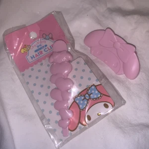 Rosa hårklämma med rosett my melody  - Söt rosa hårklämma med en stor rosett. Perfekt för att ge en gullig touch till din frisyr. Kommer i en förpackning med prickigt mönster och en illustration av en karaktär med rosett. Karaktären heter My melody