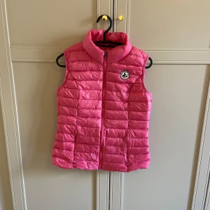 Rosa dunväst från JOTT - Säljer en snygg rosa dunväst från JOTT med dragkedja framtill. Västen har en hög krage och ett märke på bröstet. Endast använd en gång så den är i princip ny! Har kvar påsen som man kan stoppa ner den i och det är pga den som västen ser lite knöglig ut, då den varit nedstoppad i sin påse (försvinner vid användning). 💕storleken står ej på västen men den funkar för både xs och s! Inköpspris är ca 1700