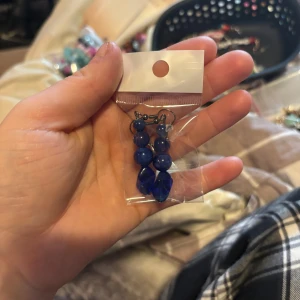 Blå pärlörhängen - Snygga blå örhängen med pärlor i olika storlekar. De har en elegant design med flera runda pärlor och en större droppformad pärla längst ner. Perfekta för att ge en färgklick till din outfit.