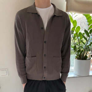 Brun kofta från Massimo Dutti - Säljer en stilren brun kofta från Massimo Dutti. ALDRIG ANVÄND! Koftan har en klassisk krage och knappar framtill. Den är ribbad och har två praktiska fickor. Perfekt för en avslappnad men ändå elegant look. 