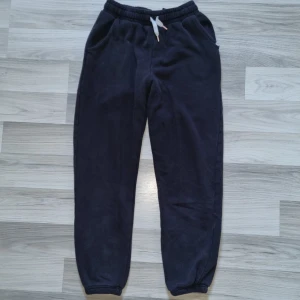 Svarta mjukisbyxor från H&M - Säljer ett par svarta mjukisbyxor från H&M med elastisk midja och snörning. Byxorna har ribbade muddar vid bensluten och 0sidofickor. Perfekta för en avslappnad stil. Har ett litet märke/nästan hål på vänster ben, lår fram.