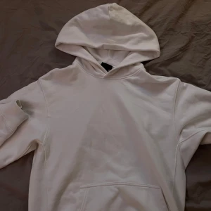 Vit hoodie från H&M - Säljer en vit hoodie från H&M i oversized passform. Den har en klassisk design med en stor huva och en praktisk magficka. 