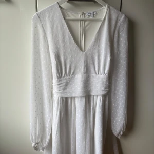 Vit prickig klänning med knytband från Bubbleroom - Säljer en vit klänning som funkar perfekt till konfirmation, student och skolavslutning. Klänningen är från Bubbleroom i storlek 38 och endast använd 1 gång. Köpt för 599kr nypris.