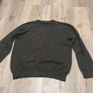 Olivgrön tröja  - Säljer en stilren olivgrön tröja från Nukutavake/ mayoral. Tröjan har en klassisk rund hals och långa ärmar, perfekt för en avslappnad look. Tillverkad i ett mjukt material som ger en bekväm passform. Passar utmärkt till både jeans och chinos.