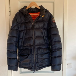 Svart dunjacka från Parajumpers - Säljer en svart dunjacka från Parajumpers med huva och dragkedja. Jackan har flera praktiska fickor och ett märke på ärmen. Perfekt för vårens kyligare dagar. Strl M-L  Skick 8/10