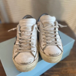Philippe model - Snygga vita sneakers från Philippe Model med blå detaljer på hälen. Skorna har en klassisk design med snörning och rund tå. Perfekta för en avslappnad stil. Storlek 40.