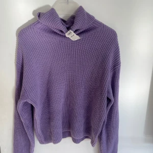 Lila stickad polotröja - Säljer en mysig lila stickad polotröja med en avslappnad passform. Perfekt för kyliga dagar med sin höga krage och långa ärmar. Ett måste i garderoben för en stilren look. Helt ny, aldrig använd, nypris: 300 kr