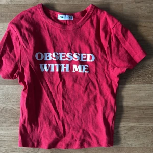 Röd t-shirt från FB Sister - Säljer en cool röd t-shirt från FB Sister med texten 'OBSESSED WITH ME' i vitt på framsidan. T-shirten har en normal passform och är kortärmad. Perfekt för en avslappnad stil!