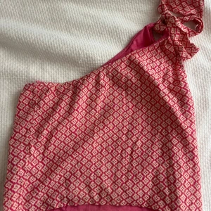 Mönstrad oneshoulder topp i rosa och vit - Säljer min snygga oneshoulder topp med ett rosa och vitt mönster från Mango