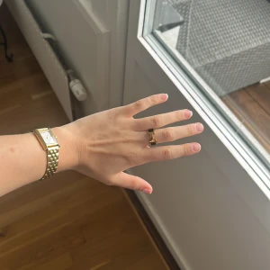 Guldfärgad ring med svart detalj - Elegant guldfärgad ring med en svart detalj i mitten. Ringen har en stilren design som passar perfekt för att ge en touch av lyx till din outfit.